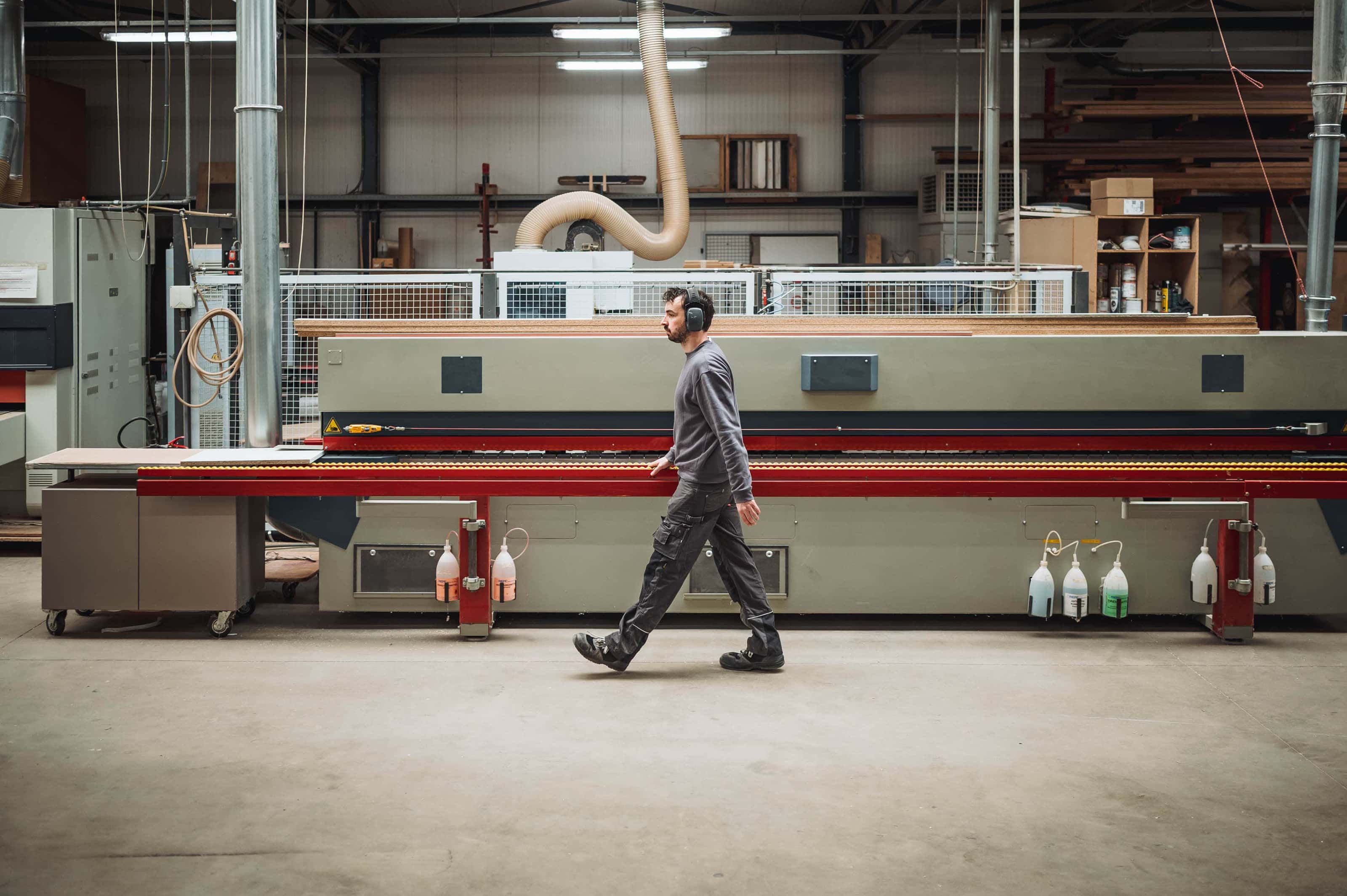 houtbewerker passeert machine in werkplaats, graffo fotografie